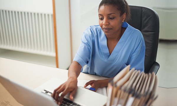 A nurse typing on a computer keyboard