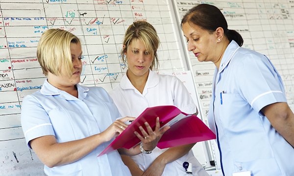 nurses confer in front of whiteboard