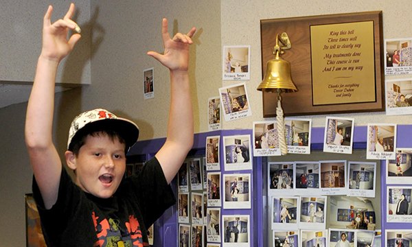 Picture of a boy ringing a bell to mark the end of his cancer treatment. Such ringing of bells is becoming more common in the NHS, though some patients object to it. 