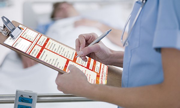 nurse holds clip board and completes paperwork to illustrate use of the Sepsis 6 tool