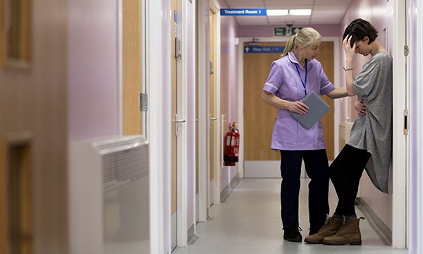 Picture of a hospital corridor where a medic is comforting a young woman. By walking in the shoes of carers whose loved ones are dying, teams of nurses are finding ways to improve support offered by their hospitals.