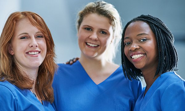 three nurses, dressed in identical uniforms, smiling