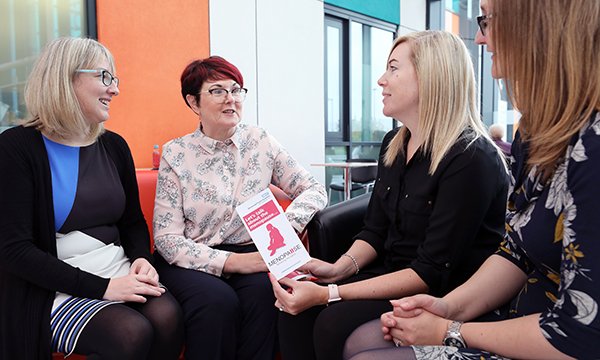 women discussing menopause in the workplace, using an information leaflet to help them