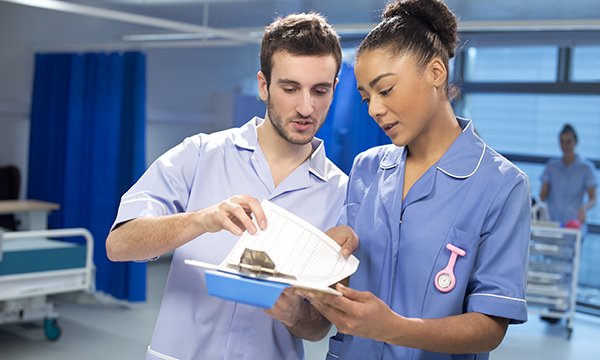 two nurses confer on a ward