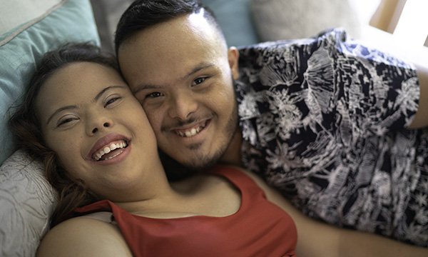 Picture shows a couple with learning disabilities smiling at the camera. Dating agencies for people with learning disabilities aim to help them find not only romance but also friendships that can reduce social isolation.