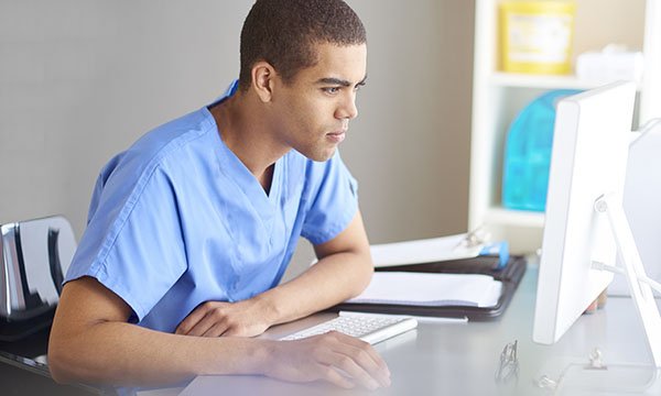 Picture shows a healthcare worker looking at a screen. New core capabilities framework may mean primary care nurses needing to top up their skills and knowledge.