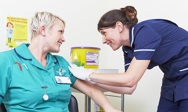 Nurse administers vaccination to a fellow healthcare worker
