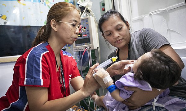 Operation Smile nurse Clark Agno-Gonzales treats a child held by a woman in Cebu, Thailand