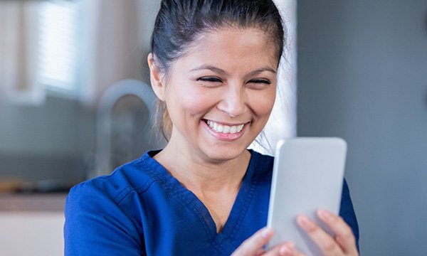 nurse smiles as she looks at her phone