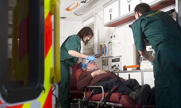 Picture shows an older man in an ambulance being treated by paramedics