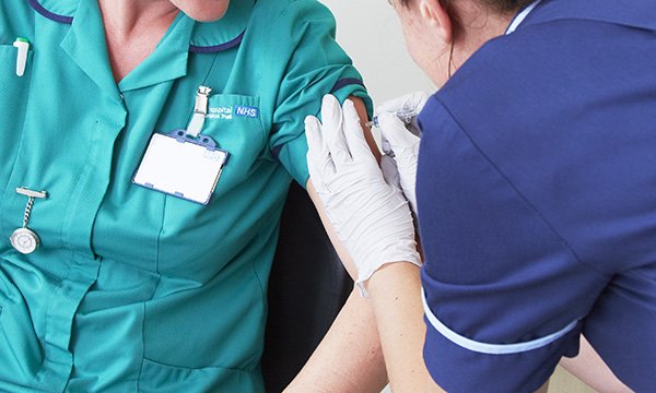 Nurse administers the flu jab to another healthcare professional in a bid to protect colleagues and patients and help ease NHS winter pressures