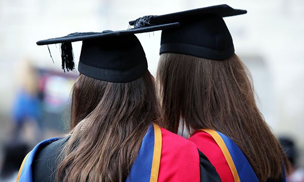 Two women dressed in mortar board and gowns for their graduation – as 2,000 nursing students face long delay to graduate as a result of the pandemic