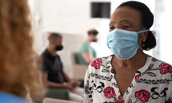 Picture shows a woman wearing  a mask in a hospital waiting room