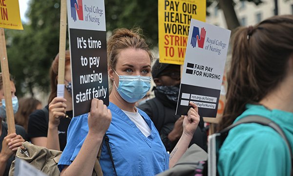 Nurse on march for pay holds RCN placard calling for fair pay for nursing