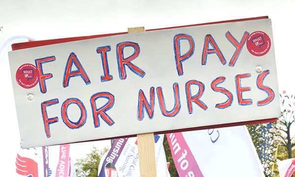 Handwritten banner says 'fair pay for nurses' as figures show steep rise in agency fees to cover nursing shifts in the NHS