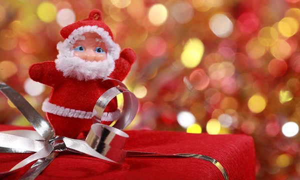 Close up of a Santa decoration standing on a Christmas present