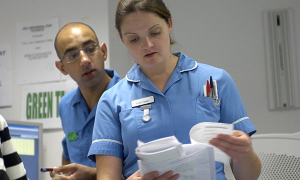 Two nurses look at a piece of paperwork at a ward-based work station: an Institute for Public Policy Research report suggests nurses’ time could be freed up if managers took on more admin 