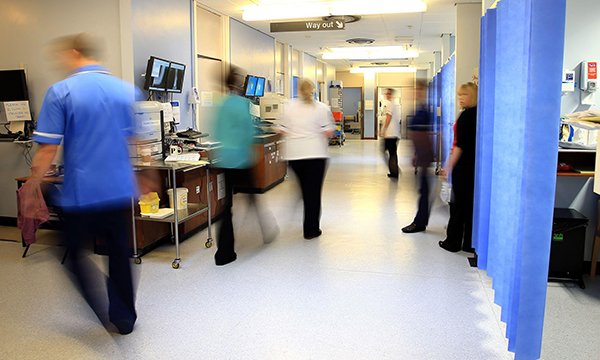 A hospital corridor with blurred staff members indicating how busy and hectic it is