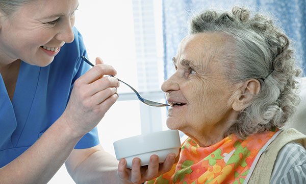 woman eats with help of nursing staff