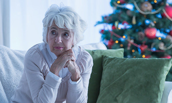 Older woman looking unhappy in room with Christmas decorations