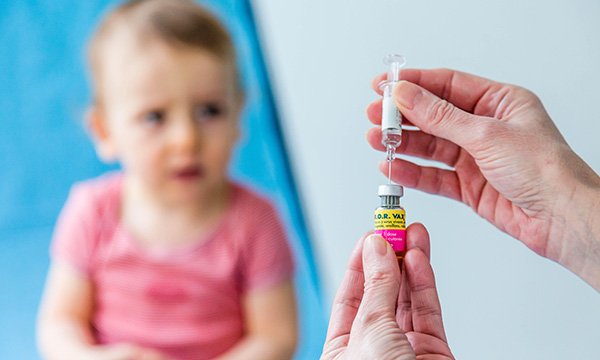 Picture shows an adult filling a syringe while a small child watches. For almost all vaccinations, at all ages, vaccination rates are lower for children with learning disabilities, a study shows.