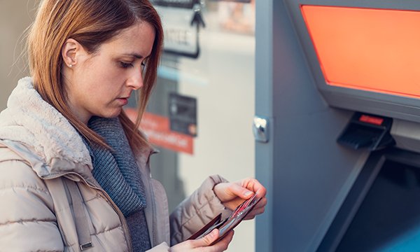 Young woman takes her bank card out at a cashpoint