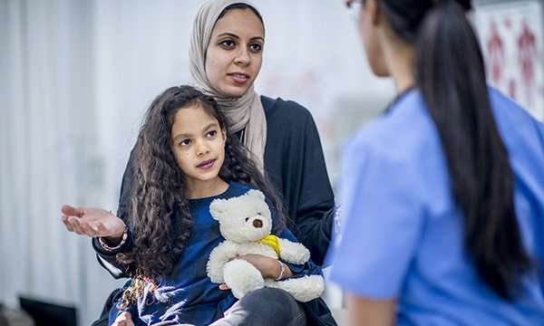 Picture shows a woman wearing a headdress holding a child while talking to a nurse. Great Ormond Street Hospital in London will host a study day on 14 November 2019 on working in a multicultural health service. 