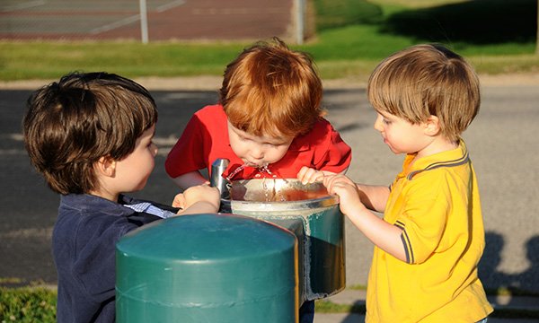 Picture shows boys taking turns drinking from a water fountain at a park. Practical information aimed at schools, nurseries and colleges to support children with bladder and bowel issues and toileting has been published by Bowel and Bladder UK.