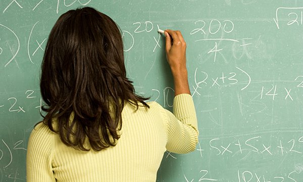 Woman undertaking maths calculation on a chalkboard