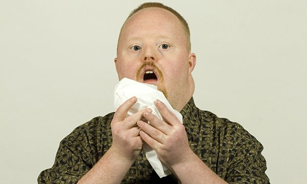 Image shows learning disability servicer user sneezing in to a tissue