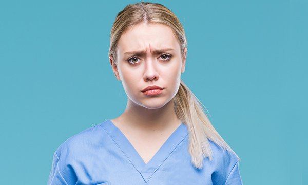 A worried-looking nursing student wearing scrubs