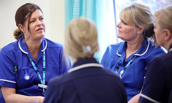 team of nurses sitting talking, showing importance of debriefing