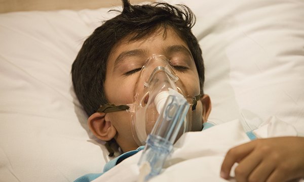 Image of a child in a hospital bed with an oxygen mask