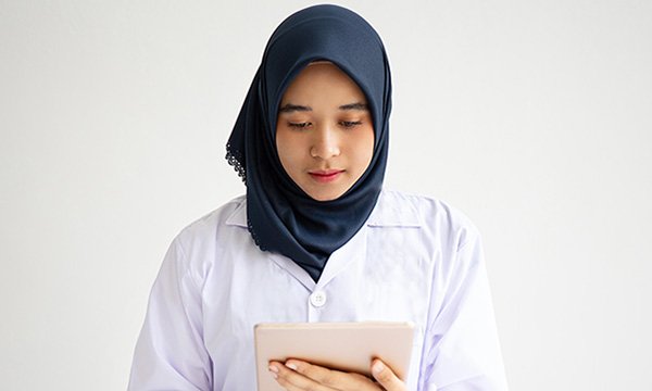 Nursing student reads from a tablet computer as students in Indonesia are offered UK virtual placement