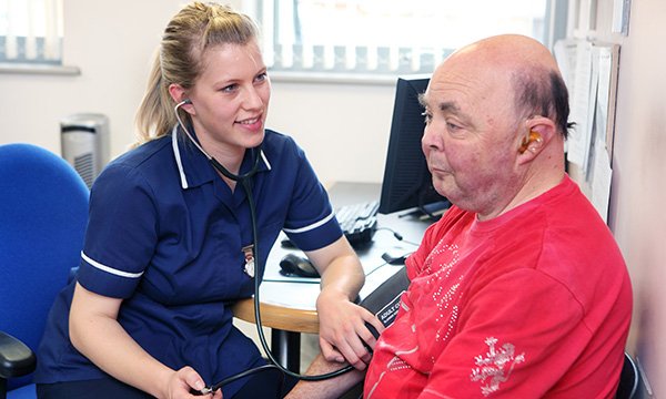 Nurse talks to man with a learning disability during a health check
