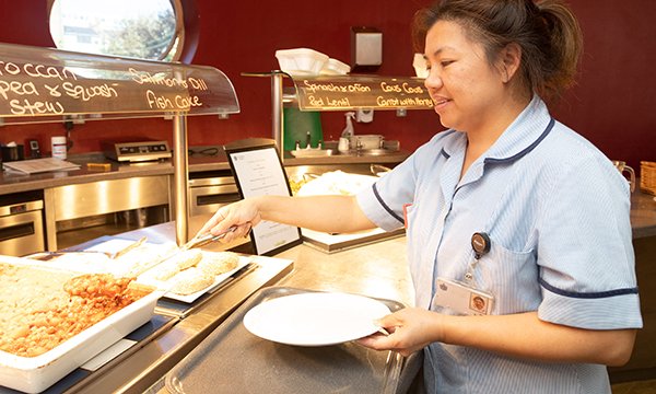 Picture shows a nurse in a canteen putting food onto her plate