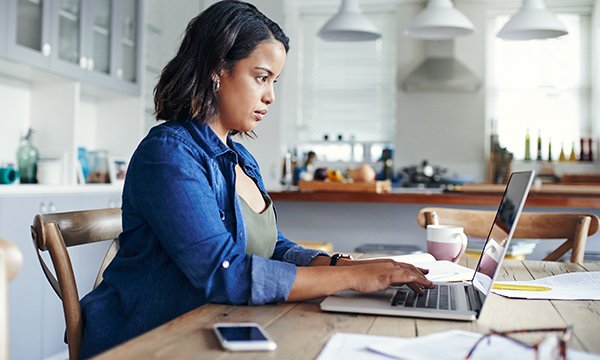 Woman works at laptop from kitchen table