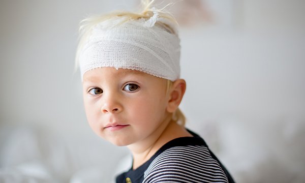 A young child with a bandaged head: head injury is a common cause of death and disability in people under 40 in the UK