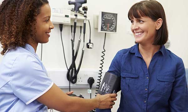A practice nurse taking a woman’s blood pressure