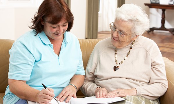A nurse sits with an older woman and goes through her patient notes