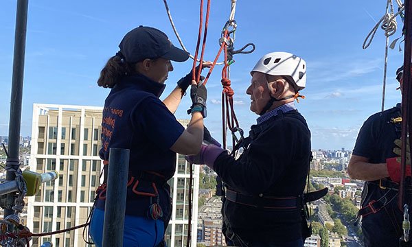 Colin Bell at the top of the Royal London Hospital building attached to a harness before his record-breaking abseil