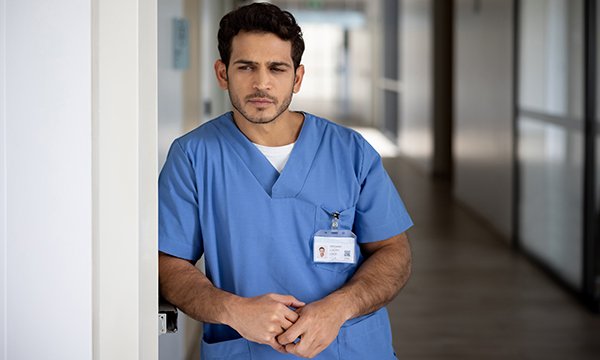 A stressed looking nurse stares into the distance in a hospital corridor