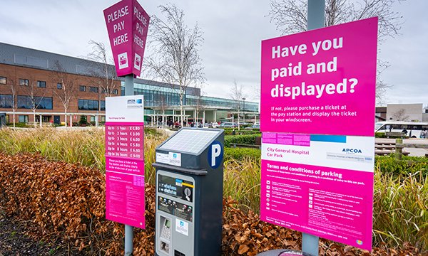 Car park pay machine and pay-and-display signs in a hospital car park – hospital nurses face charges and fines for parking at work