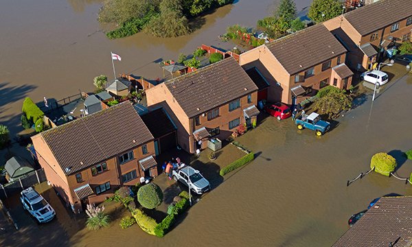 An aerial view of a row of semi-detached houses surrounded by flood water