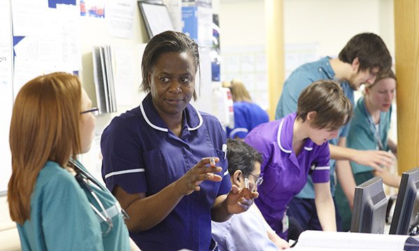 Scenes from a busy emergency department: in the foreground a senior sister updates another member of staff on care priorities